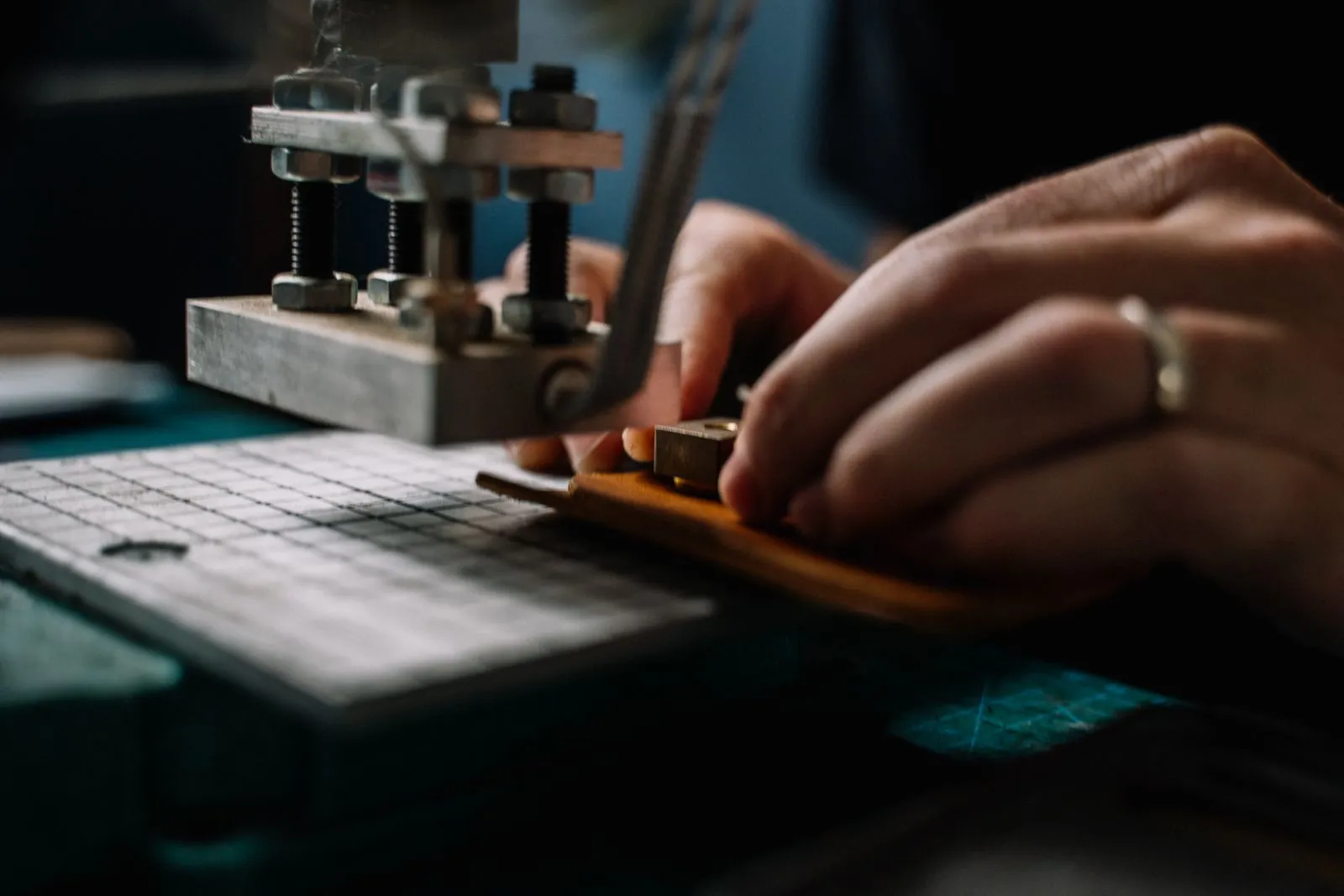Close-up of a leather artisan using metal tools to craft leather goods in a creative workspace.